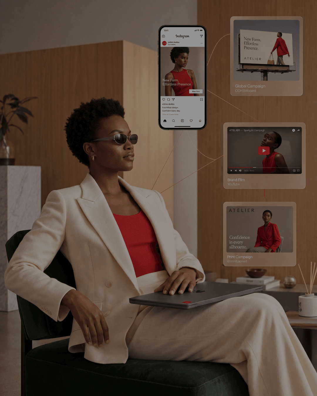 A woman in a cream suit seated in a wood-panelled interior with a laptop closed on her lap, floating panels beside her showing one campaign running as an Instagram post, an out-of-home billboard, a YouTube brand film and a print ad, linked by fine red lines