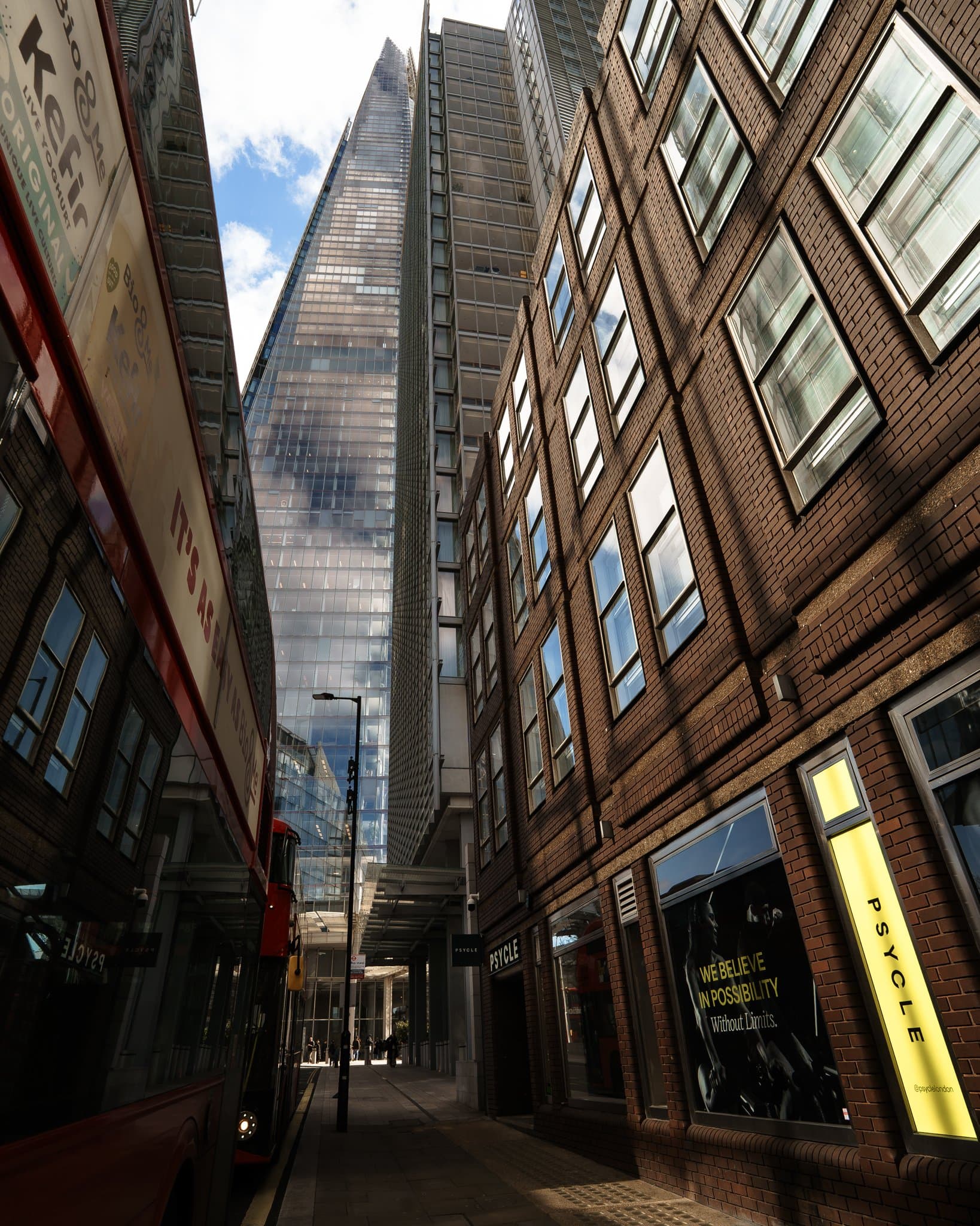 The Shard framed between dark buildings, a red bus passing beneath.