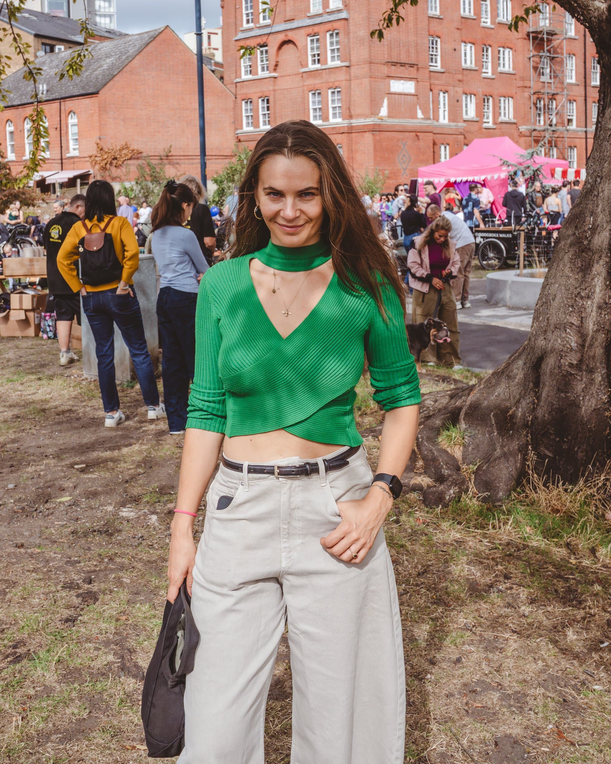 A woman in a green top standing in the festival crowd.