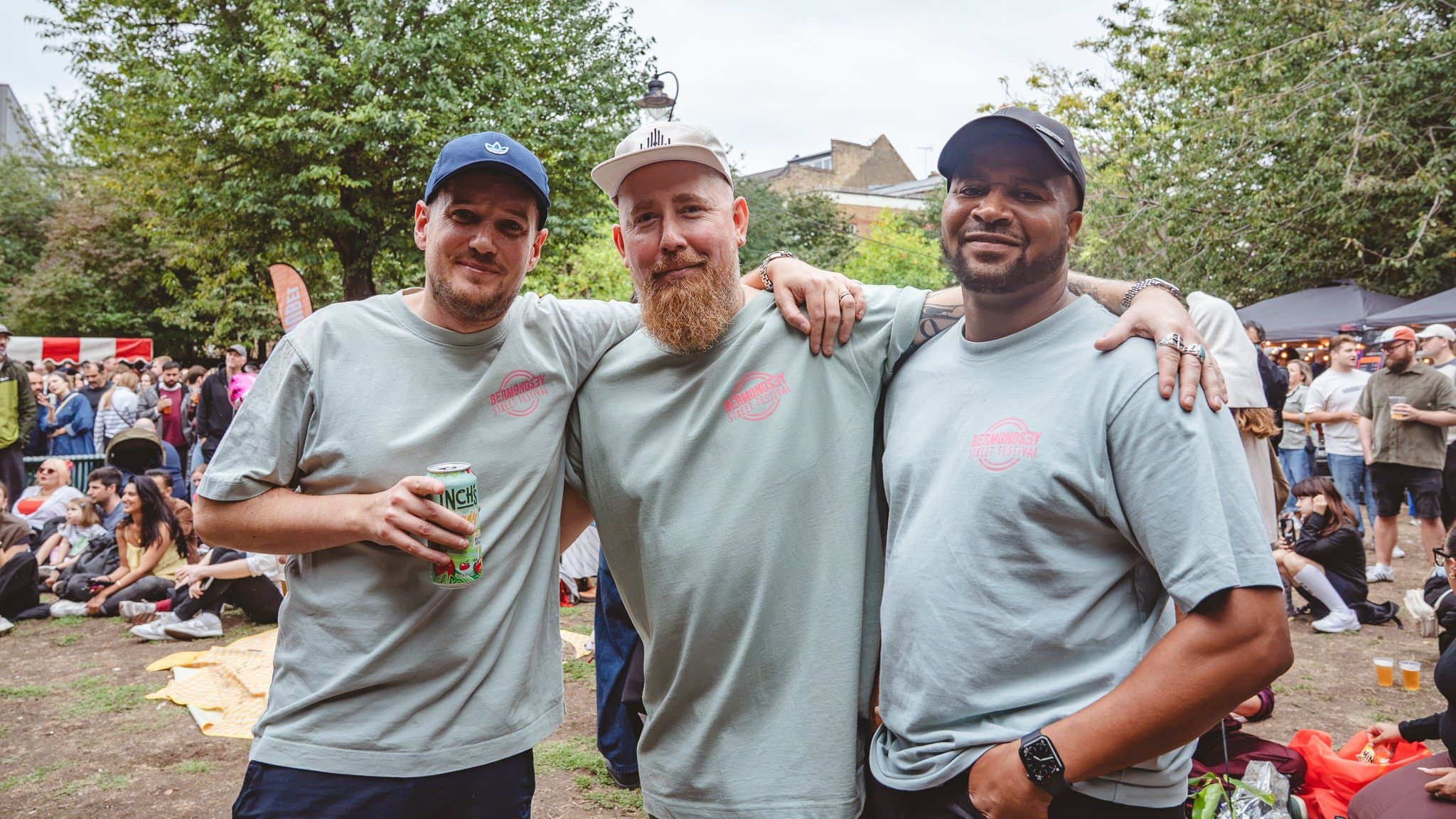 Three volunteers in festival T-shirts with their arms around each other.