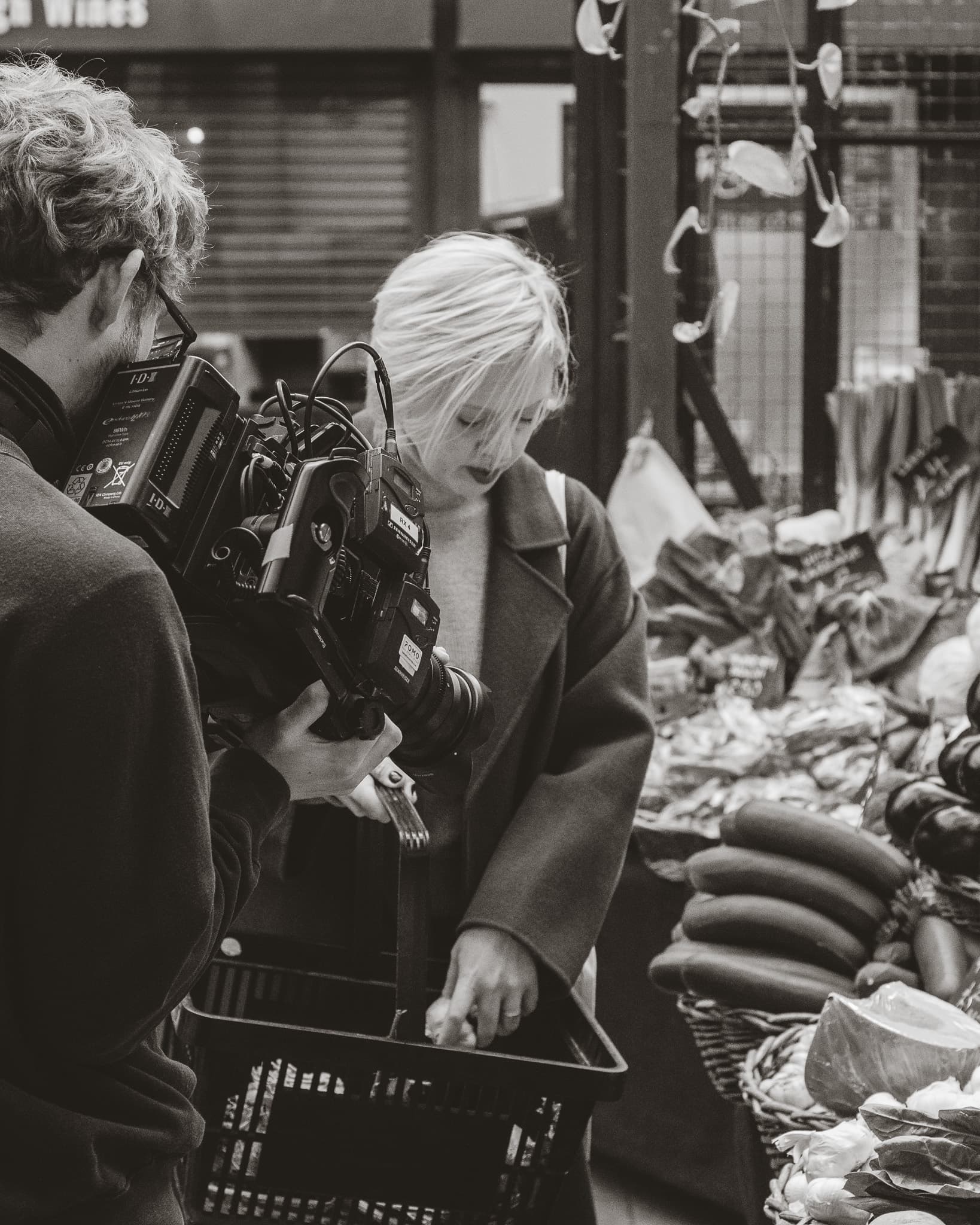 Black and white photograph of a film crew recording a woman shopping at a Borough Market produce stall.