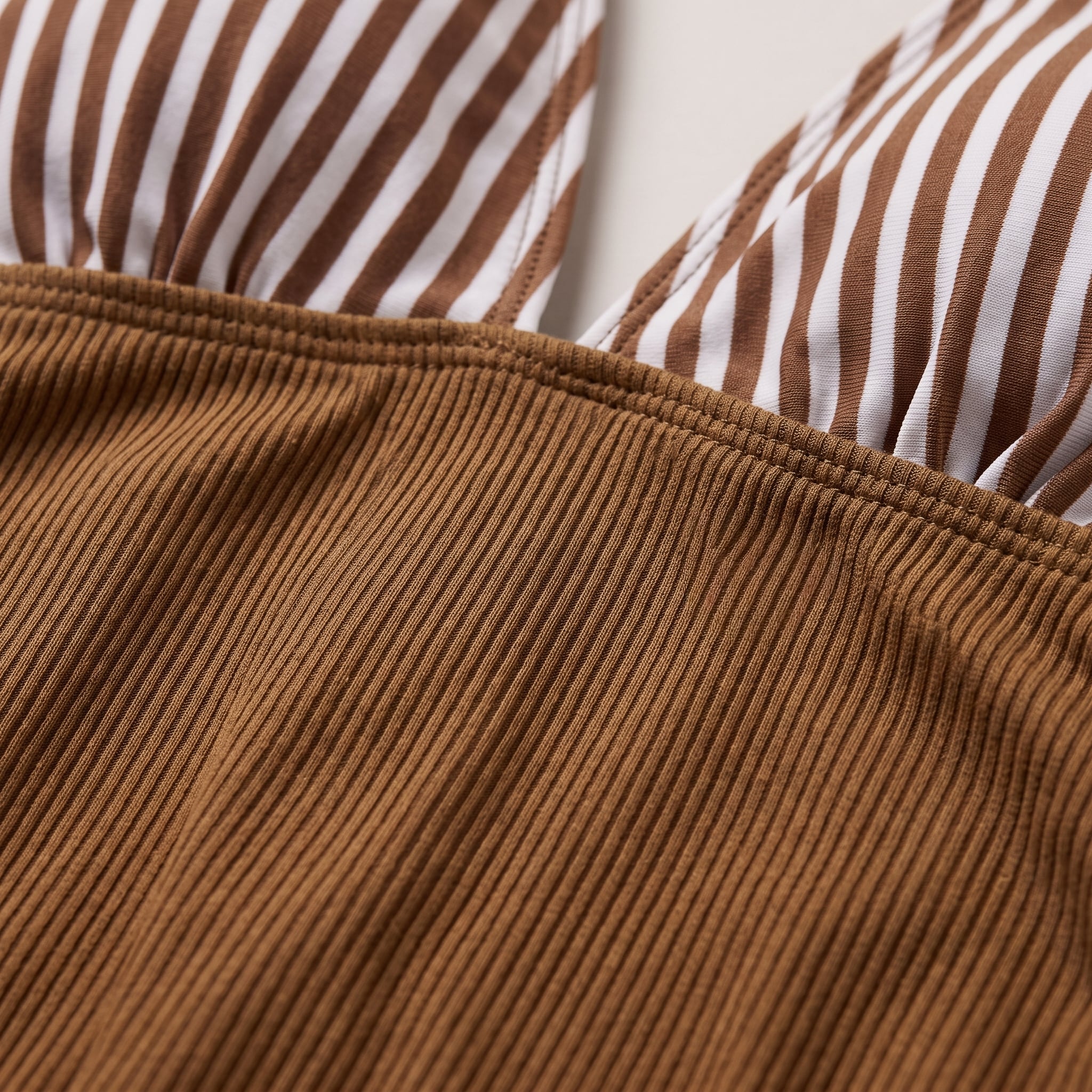 Macro crop of ribbed organic cotton jersey, the raised knit lines running in parallel across the frame